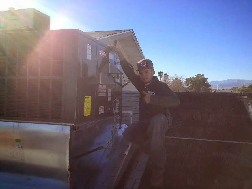 HVAC technician performing Heat Pump Repair on a rooftop unit in West Pensacola